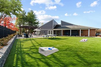 Grassy area with cornhole boards and building in background 